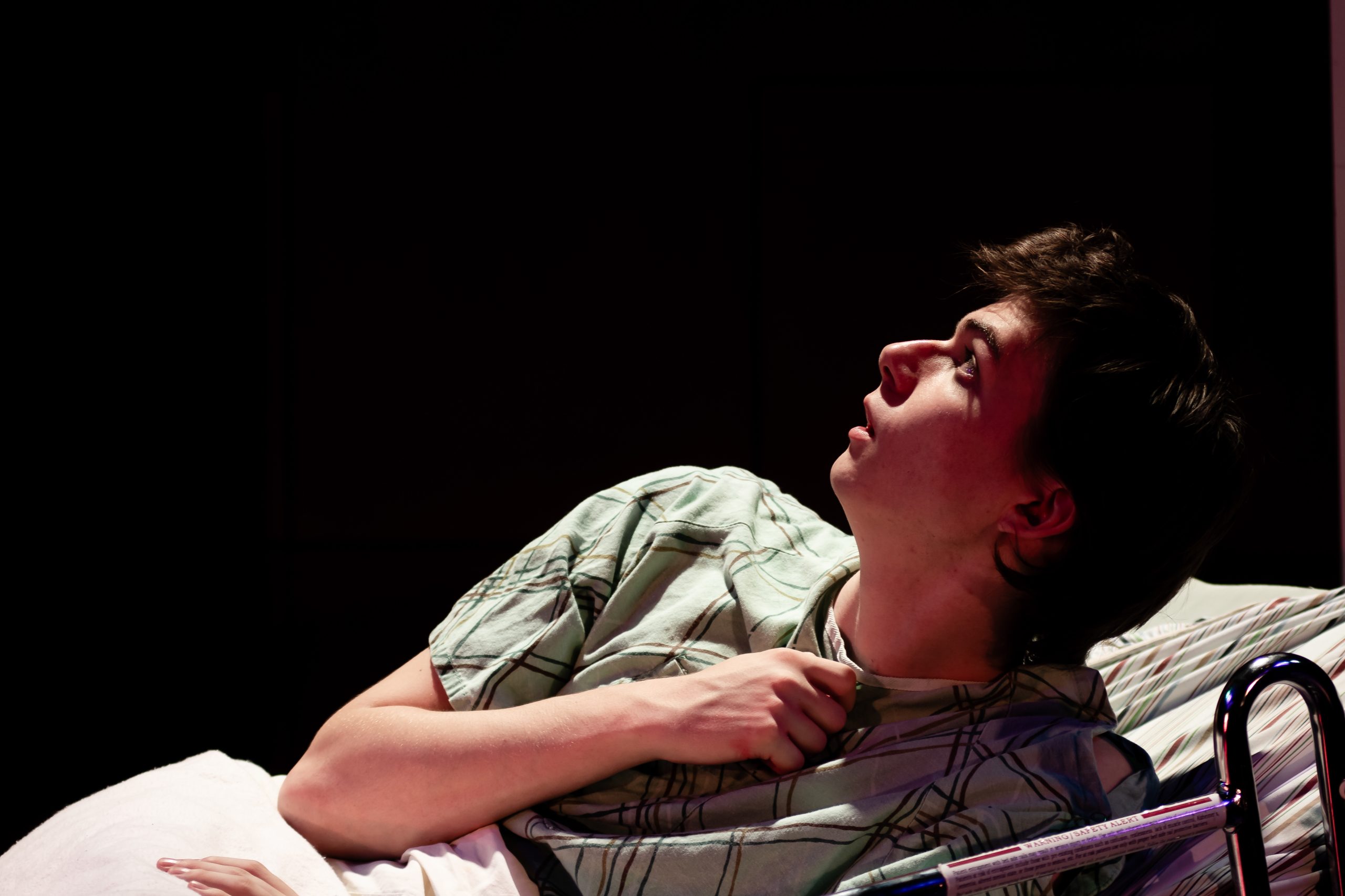 Photo from play ANGELS IN AMERICA, PART 1: MILLENNIUM APPROACHES showing a man in a hospital bed looking up.